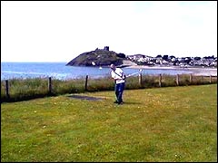Swinging a golf club at Criccieth with the castle in the background