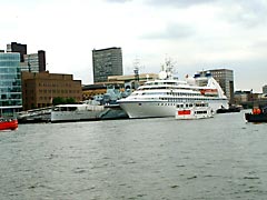 A large luxury yacht alongside HMS Belfast on the Thames in London