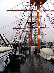 Searchlights sweep across the mast on HMS Warrior's deck